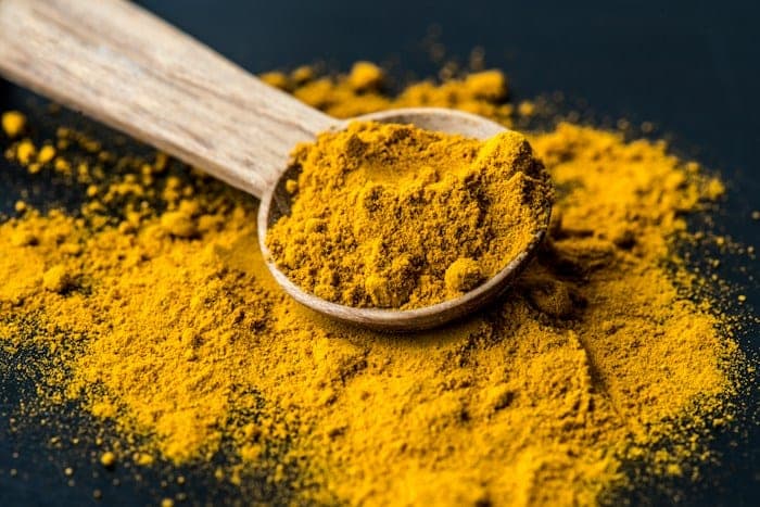 A wooden spoon of turmeric powder.